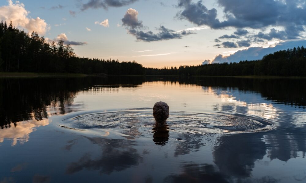 silhouette,of,a,girl,swimming,in,a,calm,lake,on