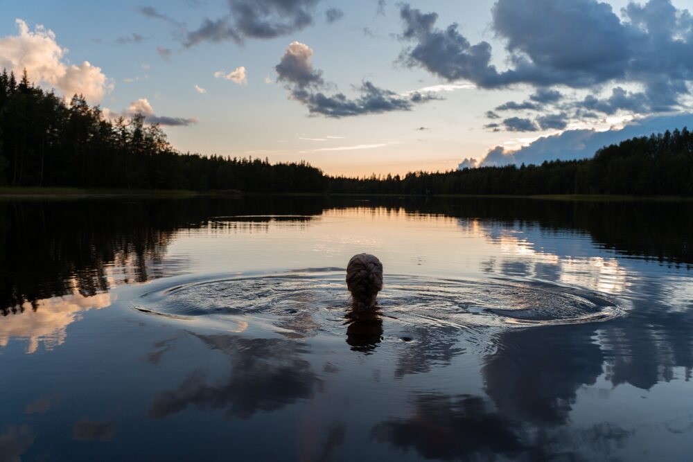 silhouette,of,a,girl,swimming,in,a,calm,lake,on