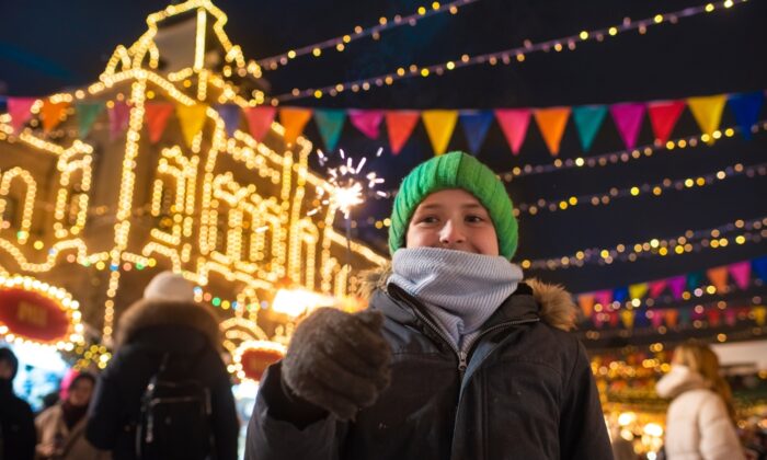 happy,boy,in,winter,clothes,holding,a,burning,sparkler,,having
