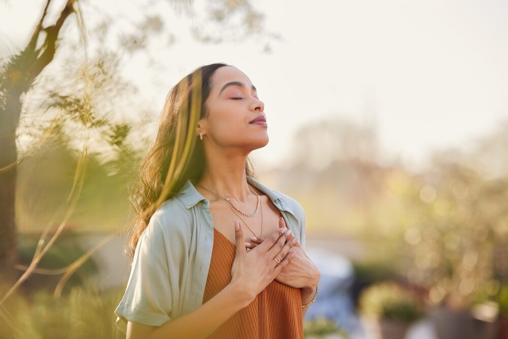 young,latin,woman,with,hand,on,chest,breathing,in,fresh