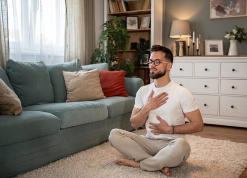 young,man,is,sitting,on,the,floor,in,his,living