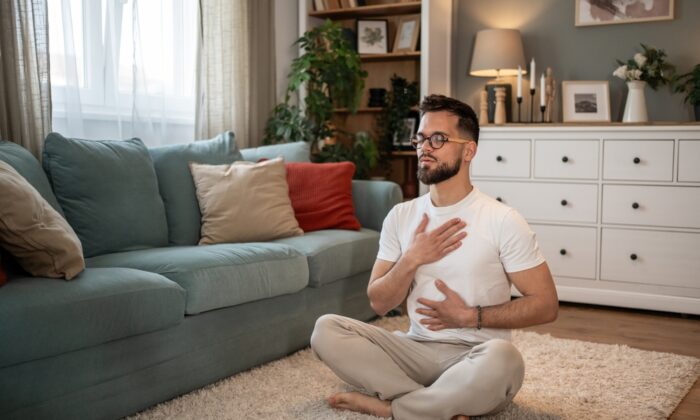 young,man,is,sitting,on,the,floor,in,his,living