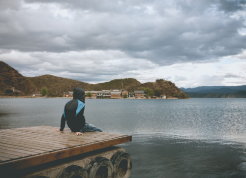 A person sitting or walking quietly in nature, surrounded by soft natural light, with a calm, contemplative feeling. The image should communicate the transition from mental noise to stillness and presence.