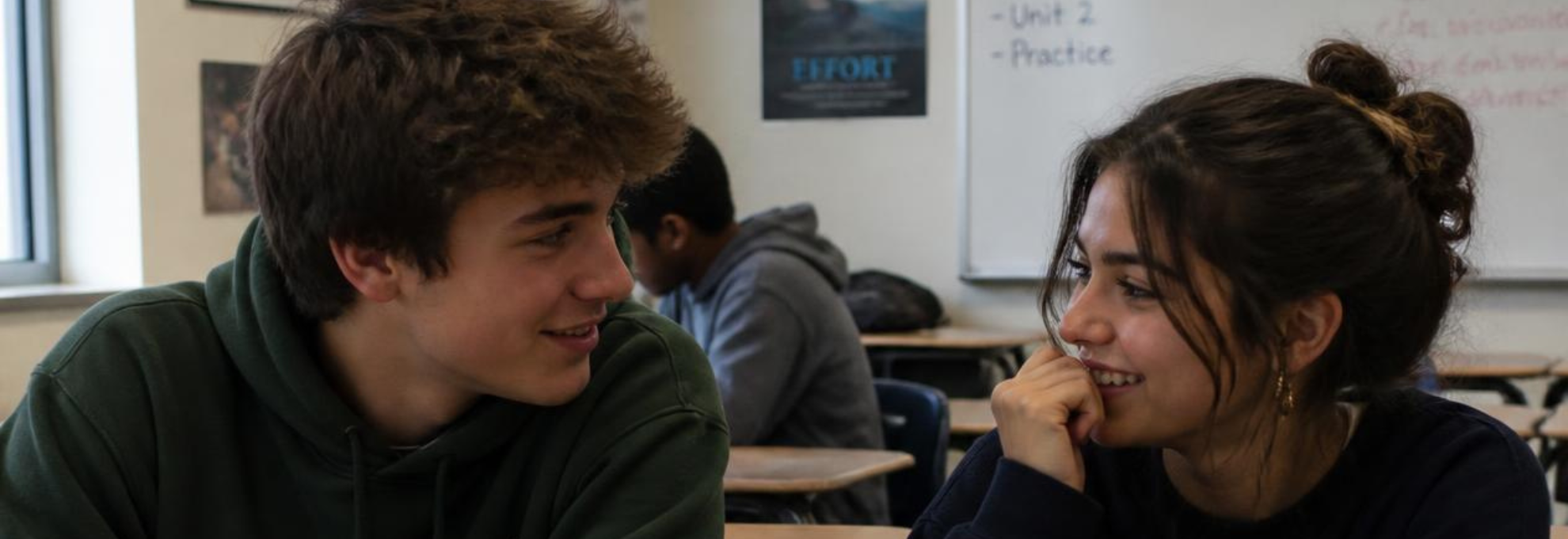 (1980 x 680 px)newsletter (12) Two students connecting naturally Two high-school students sitting together before class, talking or quietly laughing—not posed for the camera.