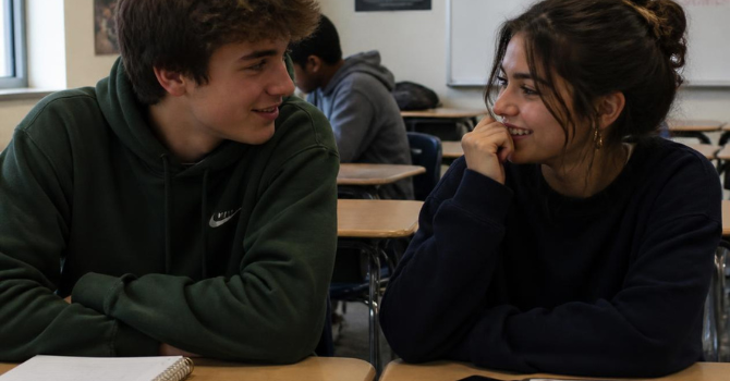 The Science of Belonging: Connection Comes First. Learning Can Grow from There. Two students connecting naturally Two high-school students sitting together before class, talking or quietly laughing—not posed for the camera.