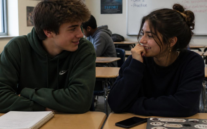 Two students connecting naturally Two high-school students sitting together before class, talking or quietly laughing—not posed for the camera.