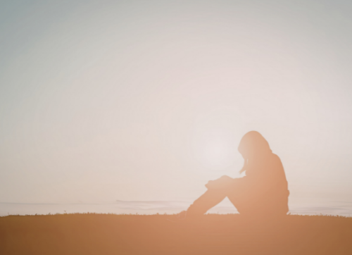 Pausing at a Mid-Thought Person sitting by the ocean in soft light, looking out in quiet thought