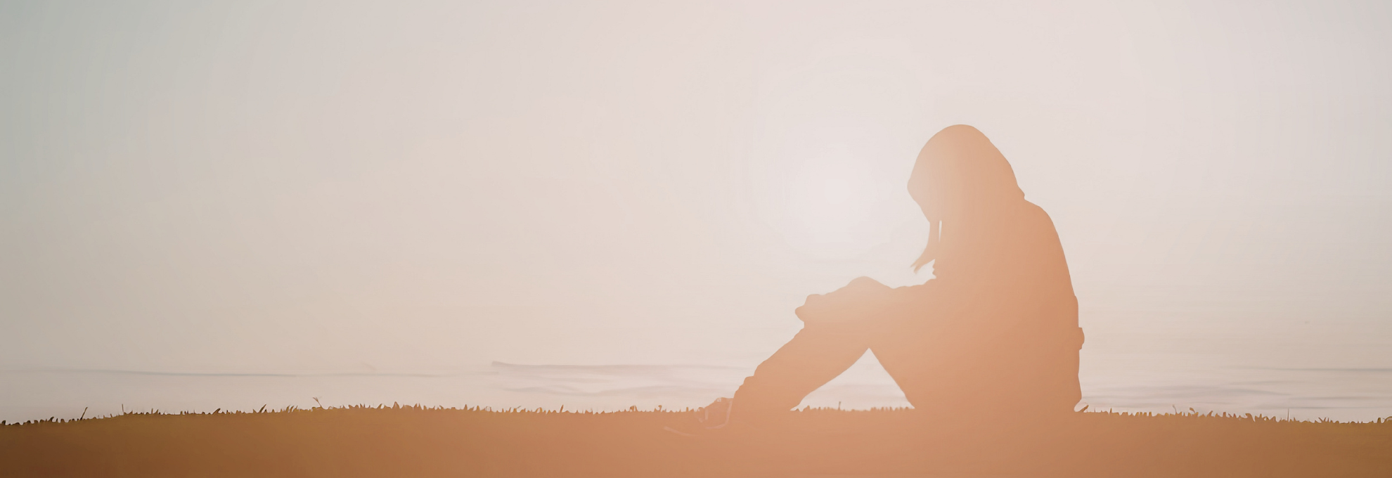 Pausing at a Mid-Thought Person sitting by a the ocean in soft light, looking out in quiet thought